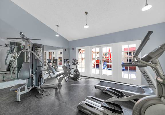 A gym with a variety of equipment including treadmills, stationary bikes, and weight machines at Urban WalkApartments on 6th Avenue, Phoenix 85016