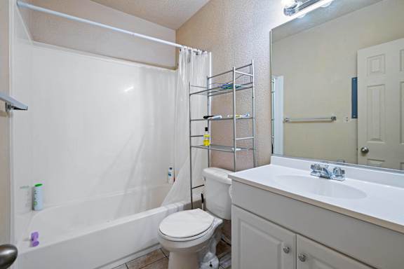 A white bathroom with a toilet, sink, and shower.