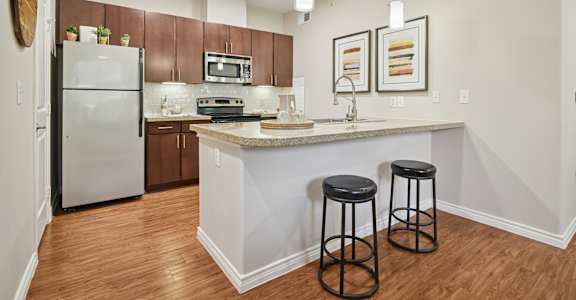 A kitchen with a white island and two black stools.