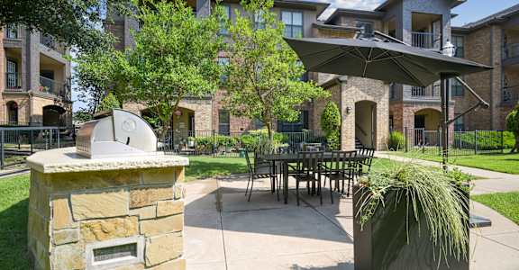 A patio with a fireplace and a table surrounded by chairs.