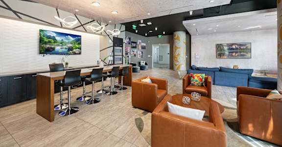 a lobby with couches chairs and a bar and a tv