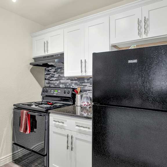 A black fridge sits in a kitchen next to a stove at Urban WalkApartments on 6th Avenue, Arizona 85016
