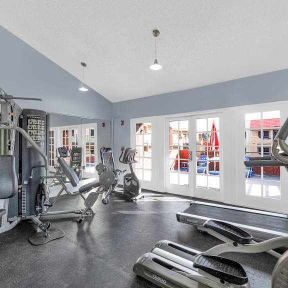 A gym with a variety of equipment including treadmills, stationary bikes, and weight machines at Urban WalkApartments on 6th Avenue, Arizona 85016