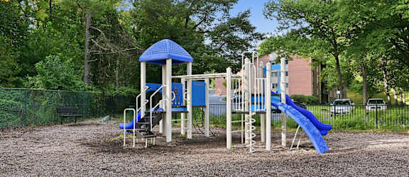 A playground with a blue slide and a wooden structure.