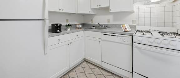 A white kitchen with a refrigerator, stove, and cabinets.