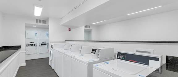 A row of white washing machines in a laundromat at Urban WalkApartments on 6th Avenue, Phoenix 85016