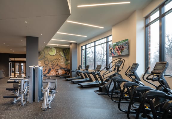 a room filled with cardio equipment and large windows at Brentford at The Mile, Virginia