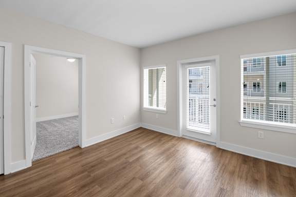 A room with wooden floors and three windows.