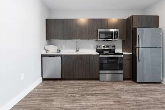A modern kitchen with dark wood cabinets and stainless steel appliances.