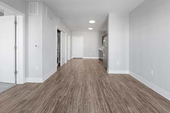 A long hallway with wood flooring and white walls.