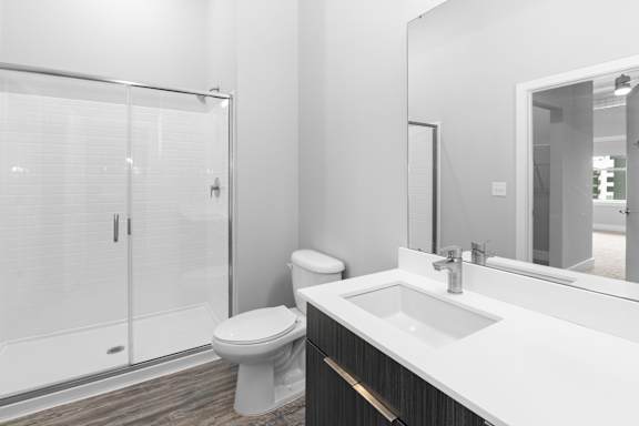 A white bathroom with a toilet, sink, and shower.