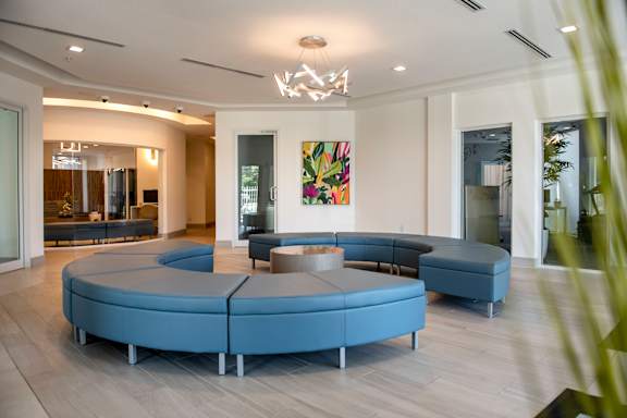 A modern living room with a large blue sofa and a painting on the wall.