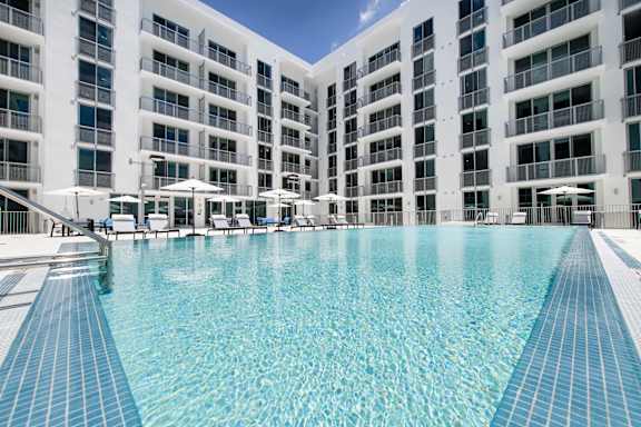 A large swimming pool in front of a white building.
