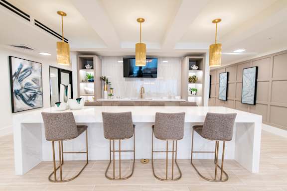A modern kitchen with a bar area and grey chairs.