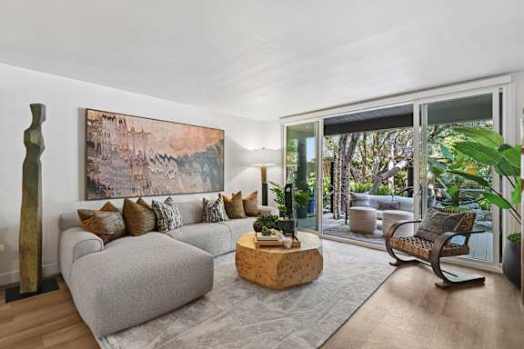 A living room with a grey couch and a large painting on the wall.