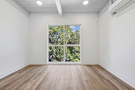 A room with a window that has a view of trees and sky.