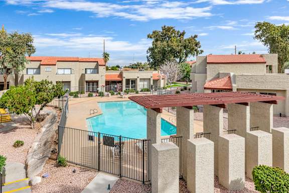 a swimming pool with a fence and buildings in the background