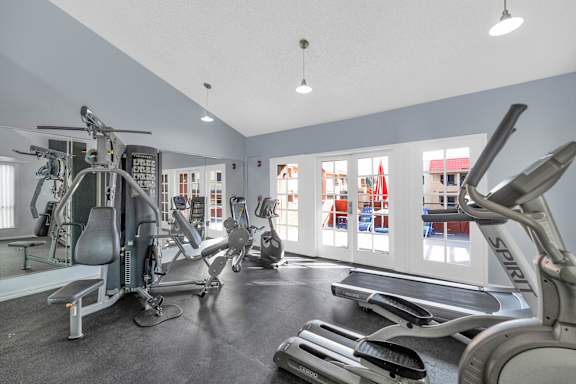 A gym with a variety of equipment including treadmills, stationary bikes, and weight machines.