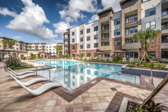 a swimming pool at an apartment building with a pool and lounge chairs at The Haven at Lake Britt Apartments, Winter Garden, FL 34787