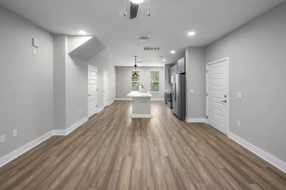 the living room and kitchen of a new home with white walls and wood flooring at The Haven at Lake Britt Apartments, Winter Garden, FL 34787