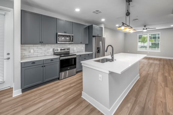 an open kitchen and living room with a large white counter top at The Haven at Lake Britt Apartments, Winter Garden, FL 34787