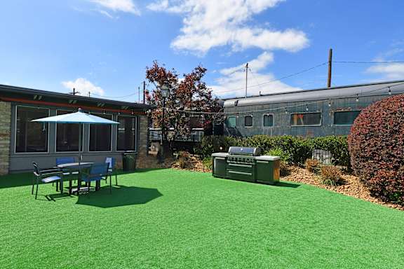 A green lawn with a table and chairs and a tree.