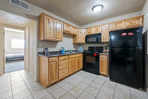 A kitchen with black appliances and wooden cabinets.