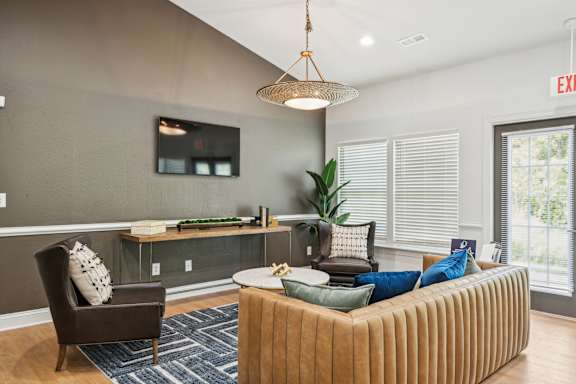 A living room with a brown chair, a brown couch, and a blue rug.