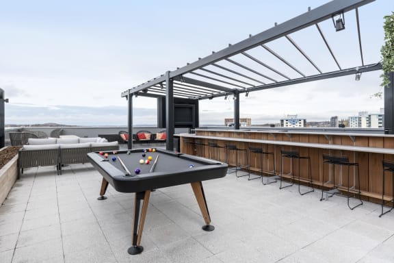 a pool table on a rooftop patio with a bar