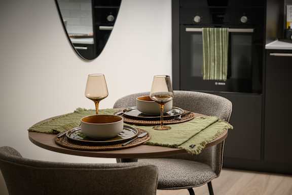 A modern dining table with two glasses of wine and two plates of food.