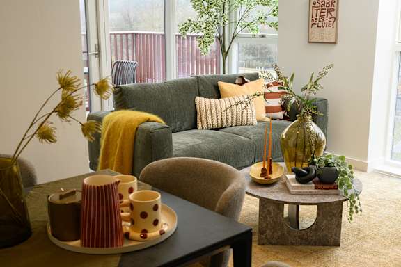 A living room with a grey couch, a coffee table, and a window.