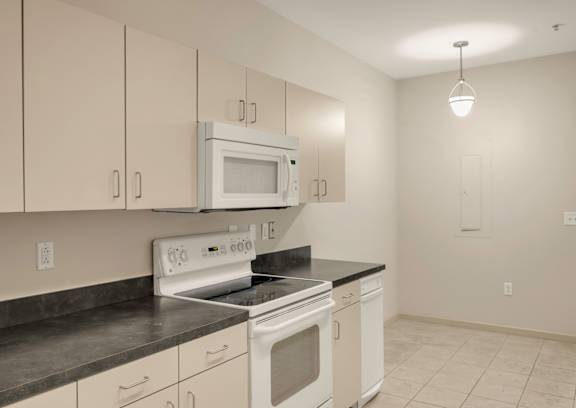 A kitchen with white cabinets and a black counter top.
