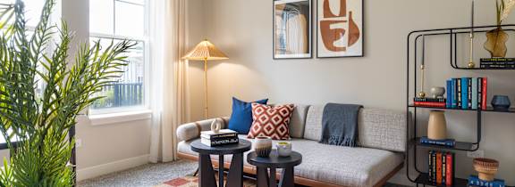A living room with a sofa, a table, a lamp, and a plant.