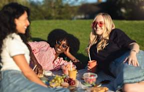 Three women enjoying a picnic in a park.