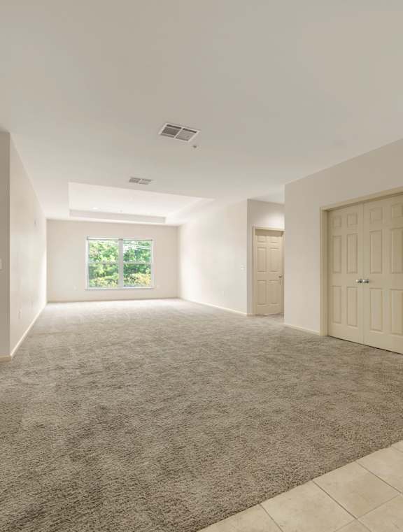 A spacious room with a carpeted floor and tiled walls.