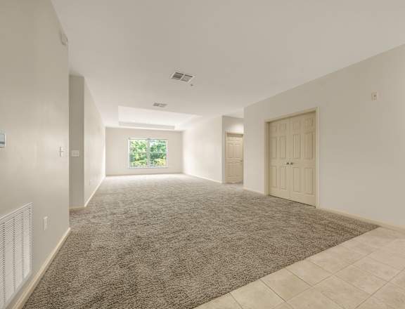 A spacious room with a carpeted floor and tiled walls.