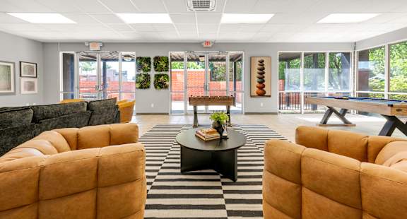 A living room with yellow chairs and a black and white rug.