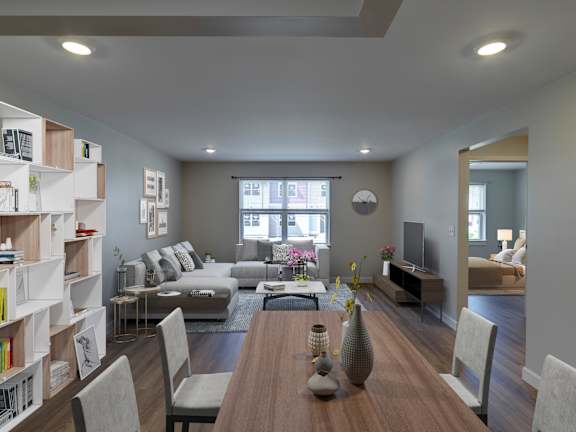 A modern living room with a wooden dining table and grey chairs at Meadows Senior Living Apartments, New Hartford, NY, 13413