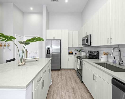 A modern kitchen with white cabinets and a marble countertop.