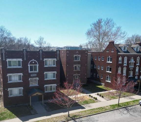 an aerial view of three brick apartment buildings on a street