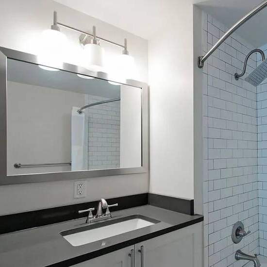 A bathroom with a black counter top and a white sink.