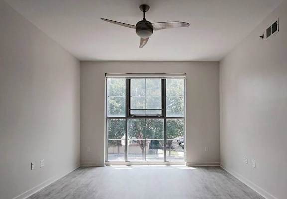 A room with a ceiling fan and a large window.