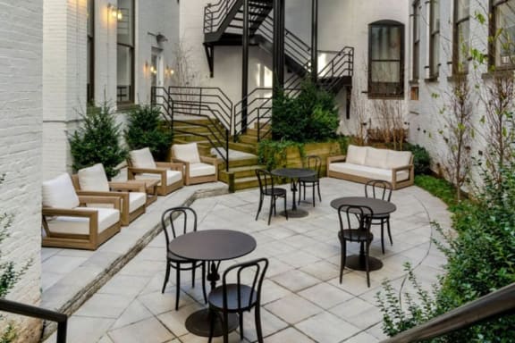 a patio with chairs and tables in front of an apartment building at Grand Adams Apartment Owner LLC, Hoboken, NJ
