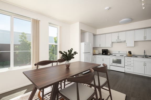 a kitchen with white cabinets and a wooden table and chairs