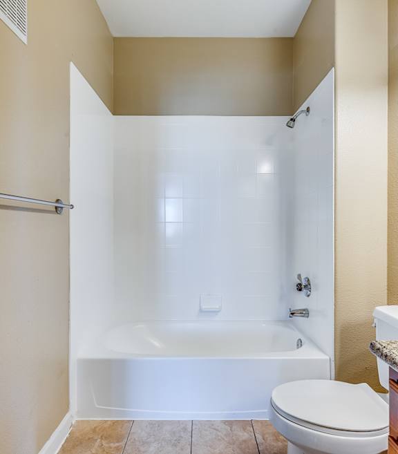 A white toilet sits next to a white bathtub in a bathroom.