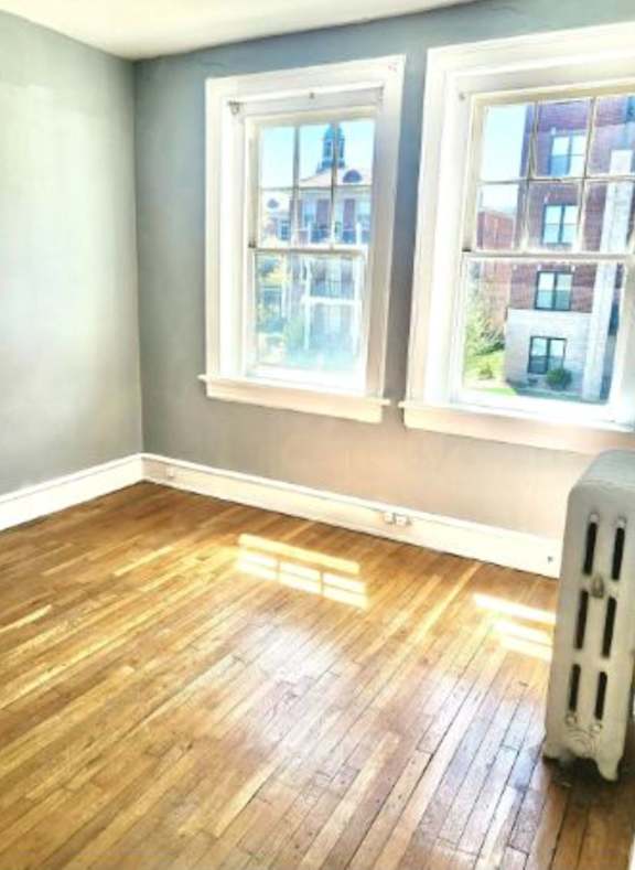 A room with a wooden floor and two windows.