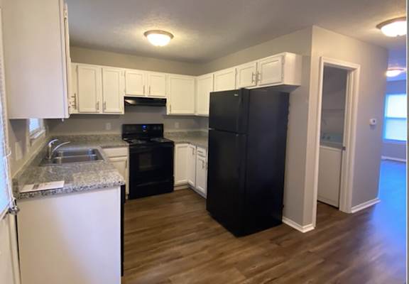 A kitchen with black appliances and white cabinets.