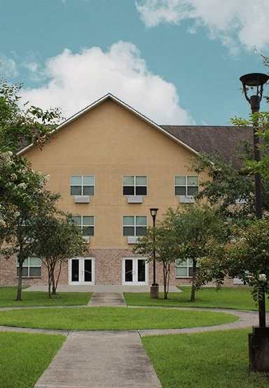 the front of a building with a lawn and trees
