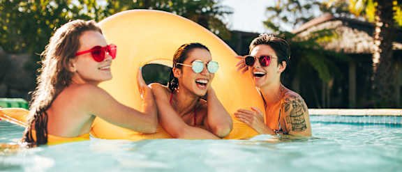 Three people are enjoying a float in a pool.