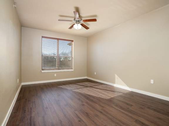 Empty room with a ceiling fan and a window with blinds.